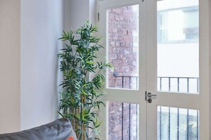 A room with a large window, a bamboo plant, and a grey sofa. - Host & Stay | Apartment 7, Stanley Street (Liverpool)