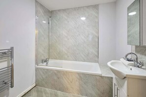 Ein modernes Badezimmer mit einer Duschkabine, einer weißen Badewanne und einem Waschbecken mit Spiegel.