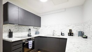 Una cucina moderna con mobili scuri, un piano di lavoro in marmo e un pavimento in legno.