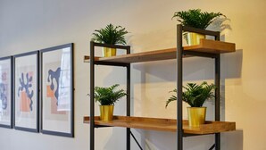 Een wandplank met drie planken, elk met een bloempot.