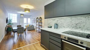 Een moderne keuken met donkere kastjes, een marmeren aanrechtblad en een inbouwoven.