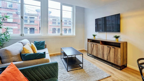 Una sala de estar con sofá, mesa de centro, televisor y aparador de madera.