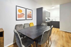 A modern dining area with a dark wooden table and grey upholstered chairs. - Host & Stay | Apartment 3, Stanley Street (Liverpool)