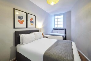 A hotel room with a large bed, a smaller bed, a window, and two framed artworks on the wall. - Host & Stay | Apartment 3, Stanley Street (Liverpool)