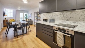 Eine moderne Küche mit dunklen Schränken, einer Marmorarbeitsplatte und einem eingebauten Backofen.