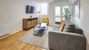 Ein modernes Wohnzimmer mit grauem Sofa, Holzschrank und Flachbildfernseher.