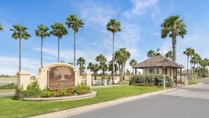 Naamplaat voor South Padre Island State Park, met een kiosk en palmbomen op de achtergrond.