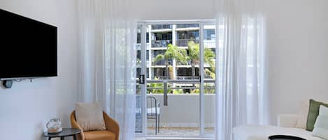 Una sala de estar moderna con un sofá, una butaca, una mesita de centro y un televisor montado en la pared.