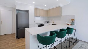 Een moderne keuken met een centraal eiland, barstoelen en een geïntegreerde koelkast.