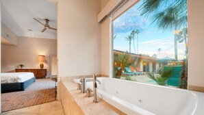A modern bathroom with a large bathtub, a ceiling fan, and a view of a pool and palm trees. - Amazing Reviews, Perfect 4 Families -Pool, Jacuzzi (Palm Springs)