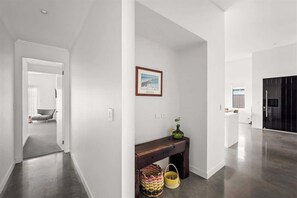 A hallway with a bench, baskets, and a framed picture on the wall. - Burnished Bay—Coastal Luxe near Abbey Beach (Abbey)