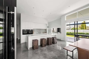 A modern kitchen with white cabinetry, a central island, and a large window.