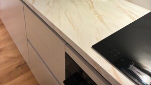 Eine Küche mit einer schwarzen Induktionskochplatte, einer Kaffeemaschine und einer Glas-Kaffeekanne.