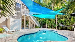 A swimming pool with a curved edge, surrounded by a brick patio and a white fence. - Ilha Bella-Private pool in Holmes Beach (Holmes Beach)