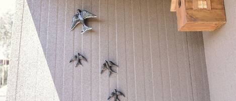 A birdhouse attached to a wall with several bird figurines arranged in a descending order.
