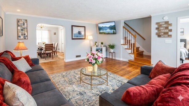 A living room with a sofa, a coffee table, and a staircase. - Chic Towson Townhome: 3BR, Bonus Suite, Deck, Free Parking - 15 Min to Baltimore (Towson)
