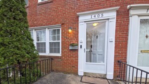 A red brick building with a white door marked "1405". - Chic Towson Townhome: 3BR, Bonus Suite, Deck, Free Parking - 15 Min to Baltimore (Towson)