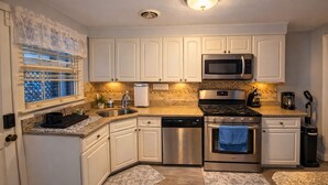 A modern kitchen with white cabinets, stainless steel appliances, a microwave, a stove, and a dishwasher. - Chic Towson Townhome: 3BR, Bonus Suite, Deck, Free Parking - 15 Min to Baltimore (Towson)