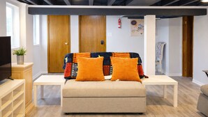 A modern living room with a sofa, two side tables, a television, and a wooden ceiling. - Chic Towson Townhome: 3BR, Bonus Suite, Deck, Free Parking - 15 Min to Baltimore (Towson)