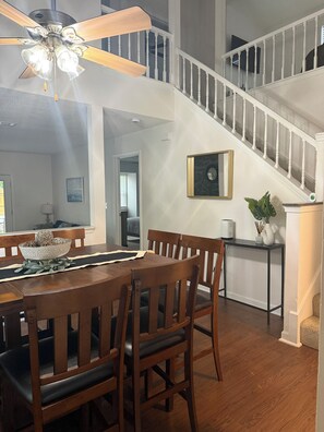 A dining area with a wooden table and chairs, a ceiling fan, and a staircase leading to an upper level. - Comfy 3-bedroom/2-bath home at the end of a cul-de-sac with all you need. (Tallahassee)