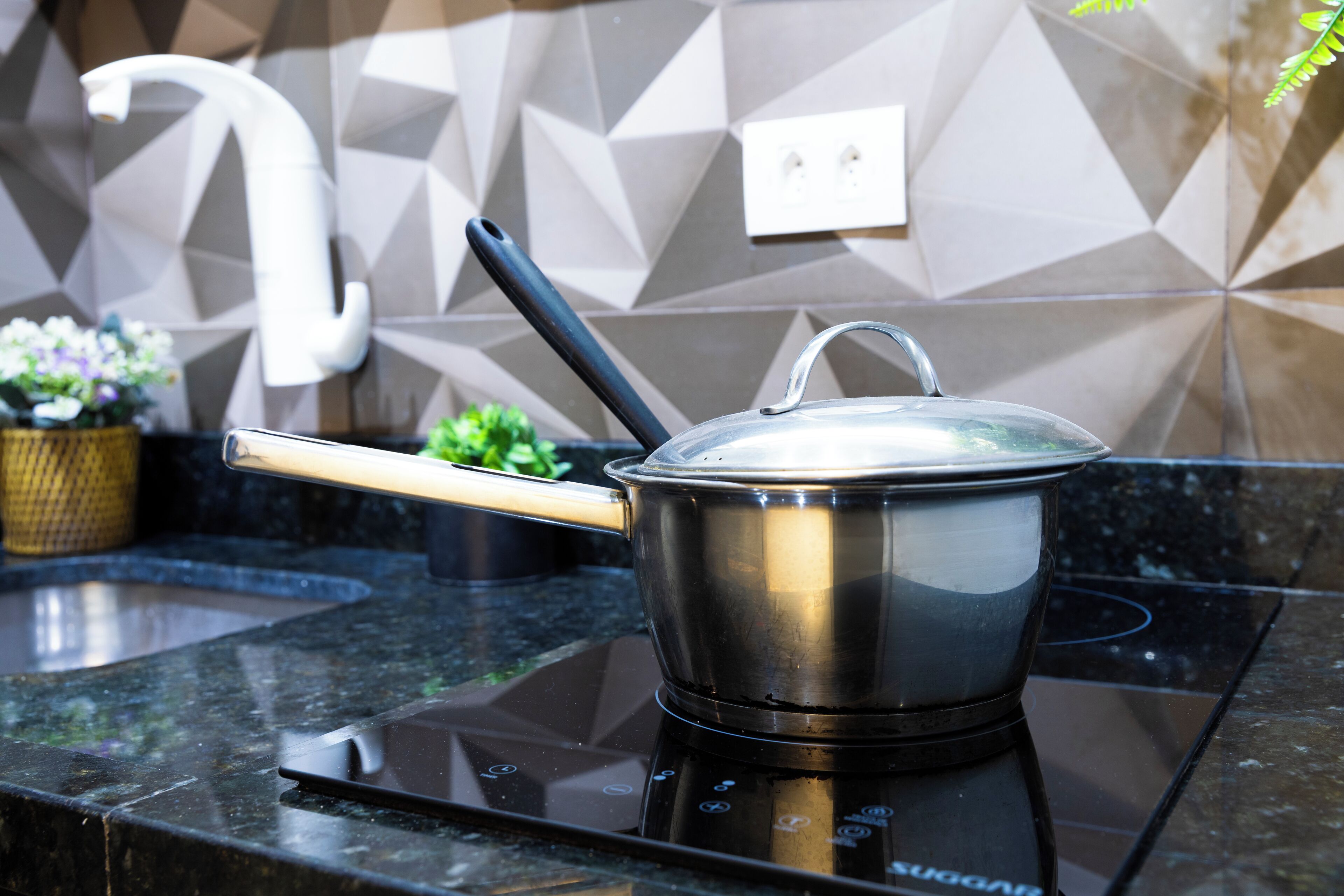 A stainless steel pot on an induction cooktop with a wooden handle.