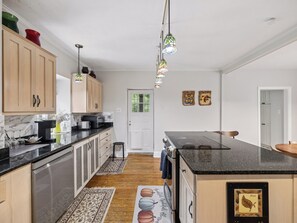 Una cocina con armarios de madera, encimera negra, estufa y pileta.
