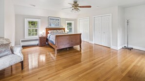 A bedroom with a wooden bed, a ceiling fan, white walls, and a radiator. - Historic 4BR/3.5BA Home near Villanova — Private Garden & Peaceful Stay
 (Villanova)