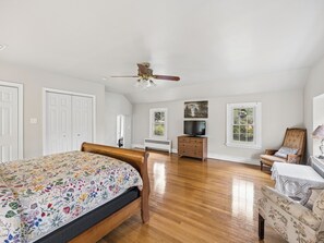A bedroom with a bed, a dresser, a television, a chair, and a ceiling fan. - Historic 4BR/3.5BA Home near Villanova — Private Garden & Peaceful Stay
 (Villanova)