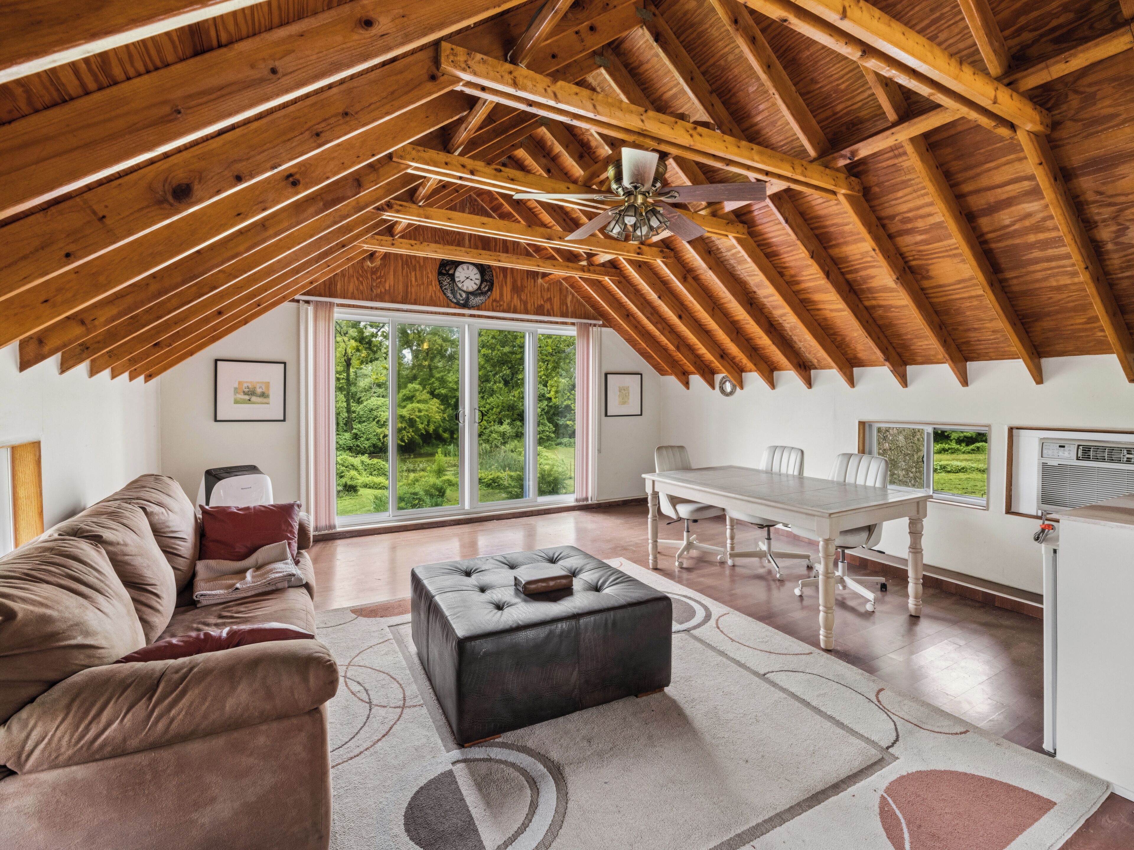 An attic room with a dining table, chairs, a sofa, and a ceiling fan.