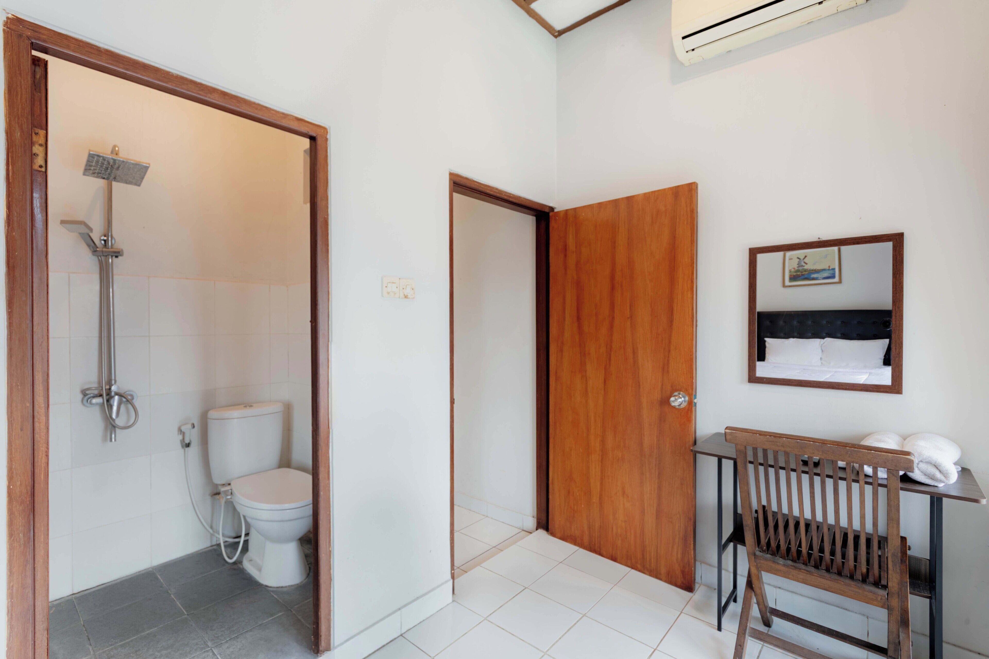 A bathroom with a shower, toilet, and a wooden bench with towels.