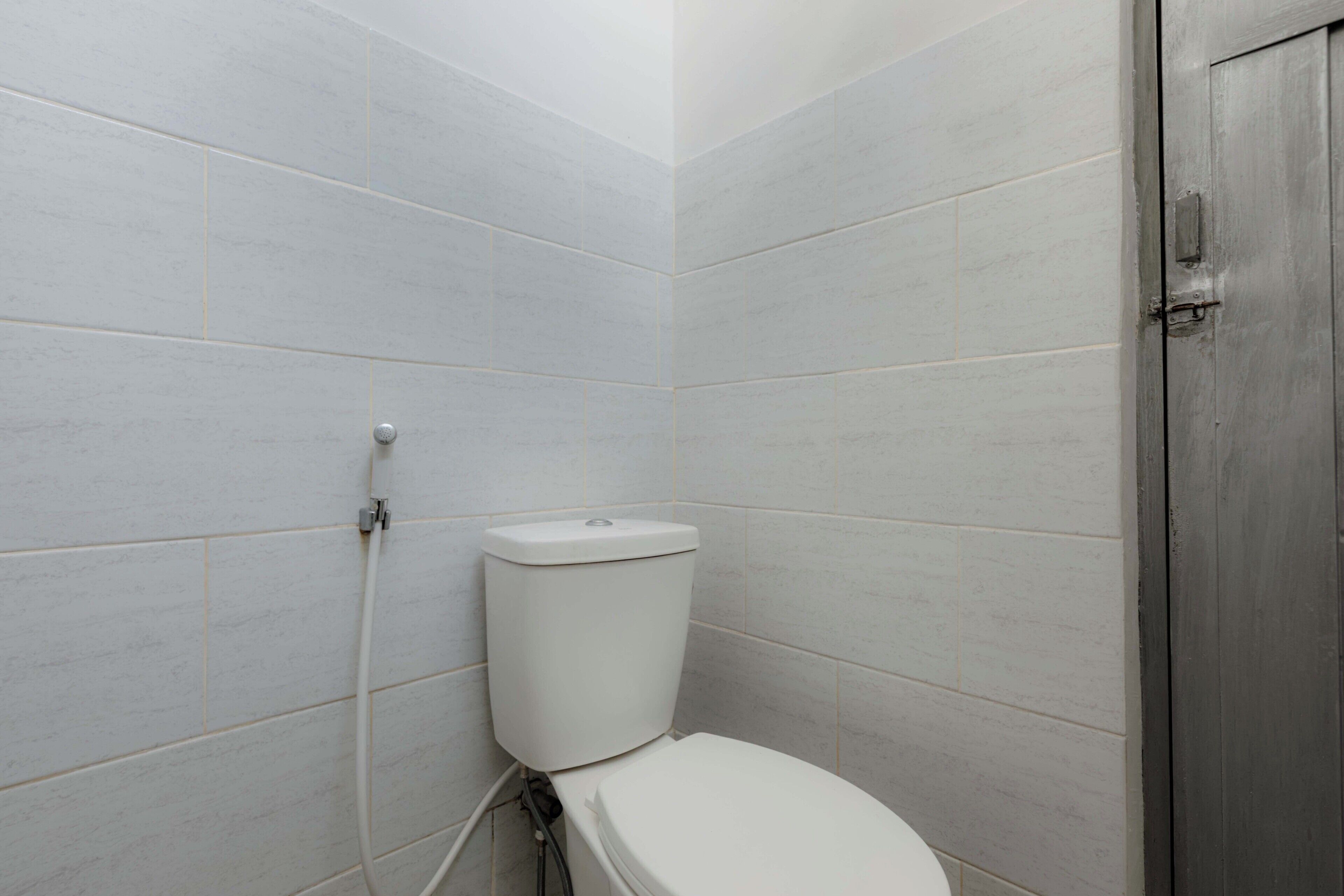 A bathroom with white tiles, a toilet, and a door.