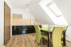 Un área de comedor con una mesa y sillas, una cocina al fondo y un tragaluz.