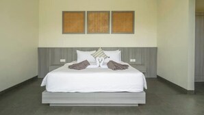 Una habitación de hotel moderna con una cama grande, cabecera gris y tres adornos enmarcados en la pared.