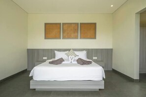 A modern hotel room with a large bed, grey headboard, and three framed wall decorations. - Villa Gantari by GORO (Gianyar Regency)