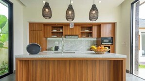 Una cocina moderna con armarios de madera, encimera de mármol y un frutero.