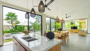Una cocina moderna con una isla grande, armarios empotrados e iluminación colgante.