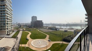 Un edificio alto con vista a un río, un puente y un parque con una zona circular.