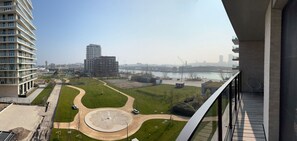 A high-rise building with a view of a river, a bridge, and a park with a circular area. - FORTESSE–Luxury apartment near the sea w/ parking (Ostend)