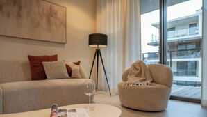 Una sala de estar moderna con un sofá, una mesa de centro redonda con un vaso y una lámpara de pie.