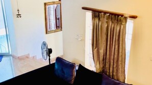 A living room with a black sofa, a black coffee table, and a window with curtains. - The Tides Inn (Chennai)