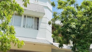 A two-story building with a white exterior and tiled roof. - The Tides Inn (Chennai)