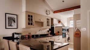 A modern kitchen with a central island, built-in appliances, and a dining area with chairs.