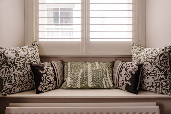 A window seat with patterned cushions and a radiator below.