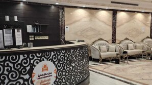 Un hall d’hôtel doté d’un sol en marbre, d’un comptoir d’accueil orné d’un motif noir et blanc décoratif, et d’un espace détente avec des canapés moelleux.