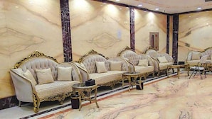 Une chambre luxueuse dotée d’un sol en marbre, de canapés richement décorés et d’un plafond orné.