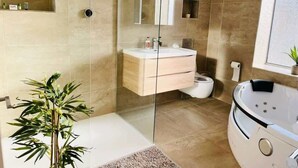A modern bathroom with a glass shower enclosure, a freestanding bathtub, and a vanity with a mirror. - Fratton House: Alver Road: Free parking (Fratton)