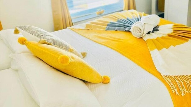 A hotel room with a bed, yellow curtains, and a window with blinds. - Fratton House: Alver Road: Free parking (Fratton)