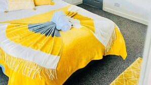 A neatly arranged bedroom with a bed, pillows, a bedside table with a vase of flowers, and a door. - Fratton House: Alver Road: Free parking (Fratton)