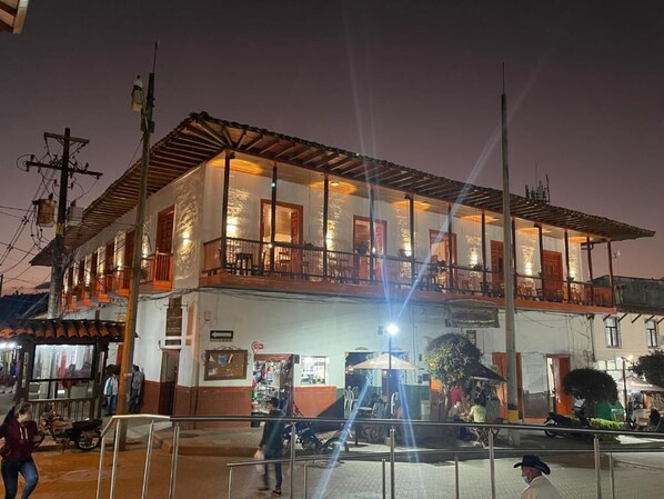 Un edificio de dos pisos con balcones, una tienda en la planta baja y una calle en frente.