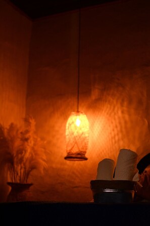 A dimly lit room with a hanging light fixture and a bowl of towels on a table. - Hotel Colonial Abejorral (Abejorral)